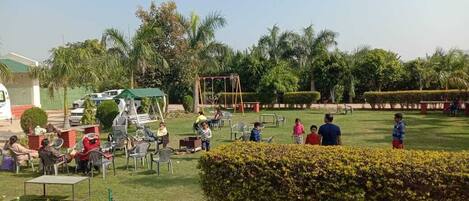 An outdoor area with seating arrangements, a playground, and well-maintained greenery.
