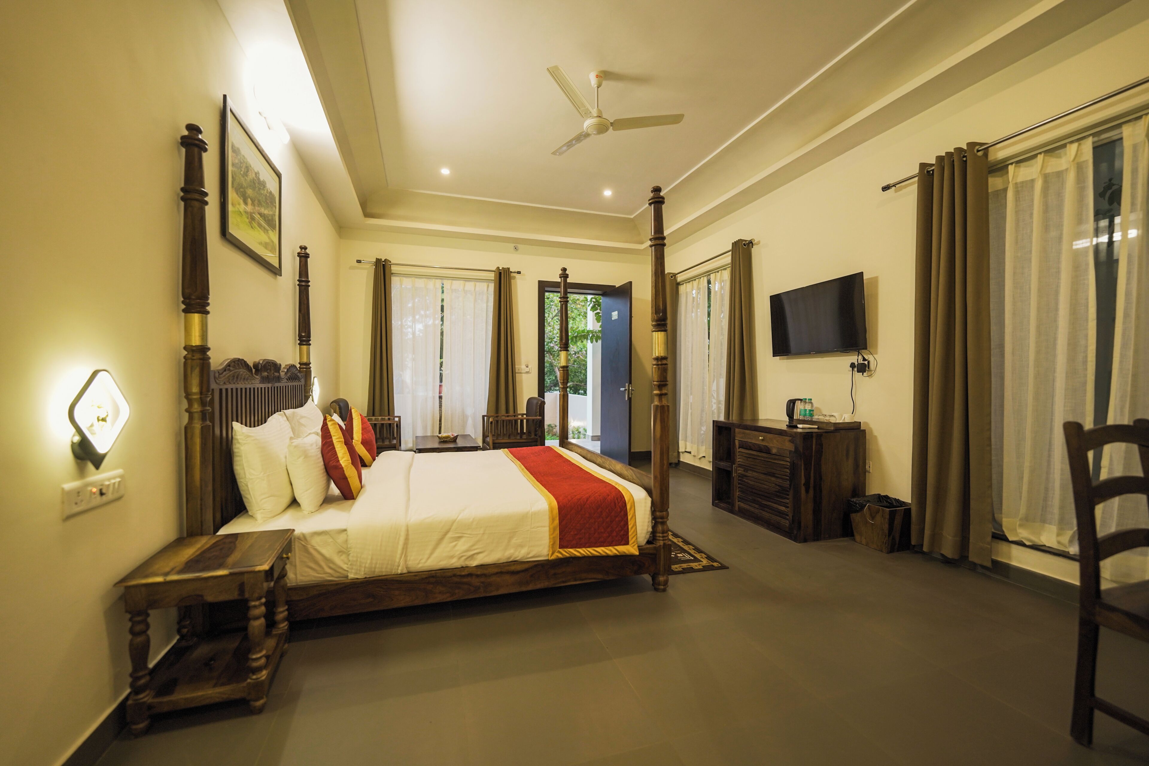 A bedroom with a four-poster bed, a television, a desk, and a chair.