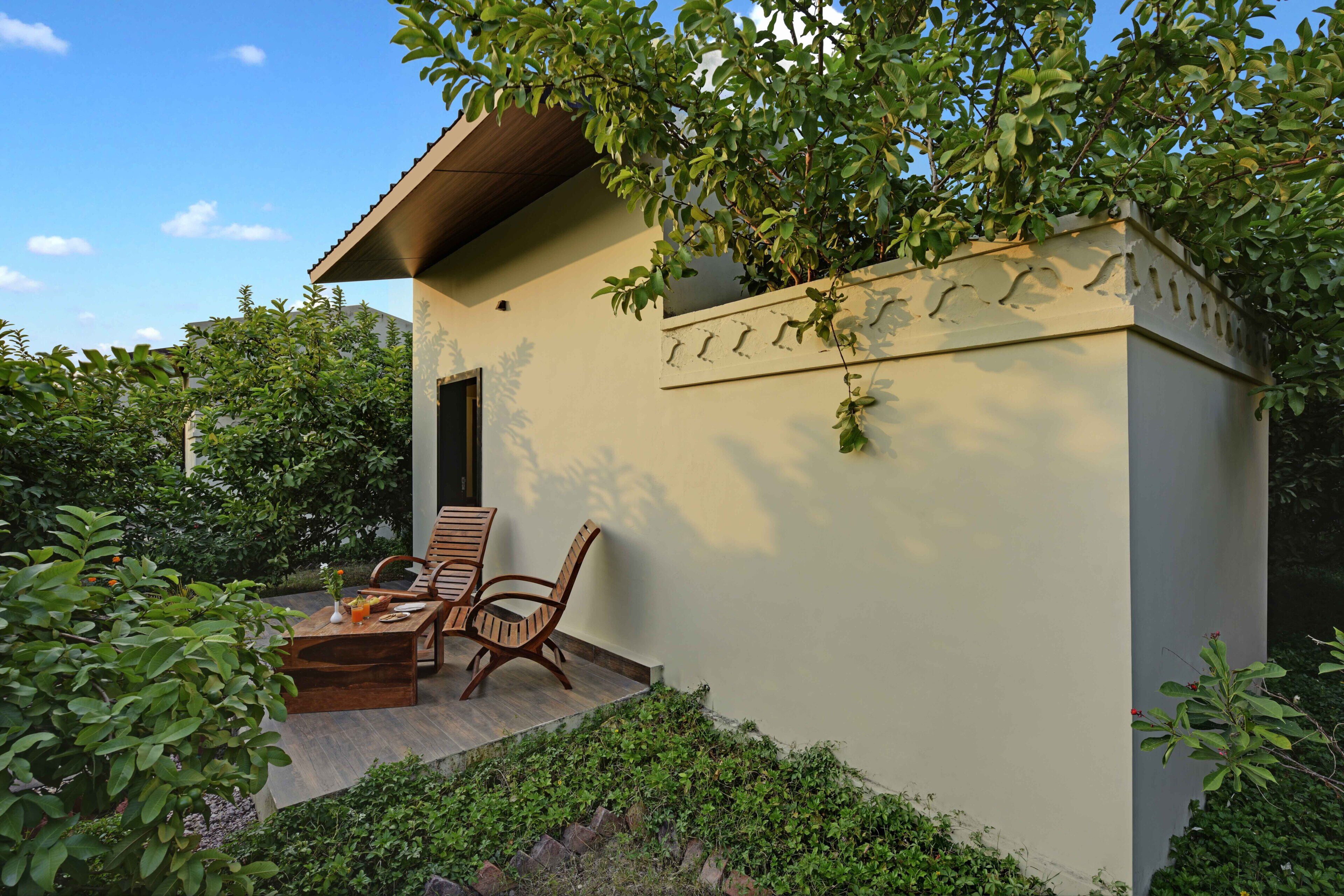 A small building with a patio area, a wooden bench, and a table with a drink.