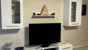 Un saló modern amb un televisor de pantalla plana sobre un moble blanc, flanquejat per armaris amb portes de vidre.