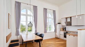 Una cocina moderna con armarios blancos, encimera de madera y una zona de comedor con mesa y sillas.
