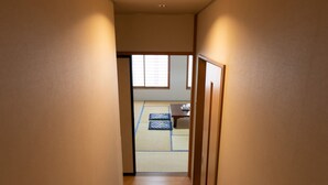 A narrow hallway leading to a tatami mat room with a low table and cushions. - Tabist Kanko Business Hotel Matsuyama Hida Takayama (Takayama)