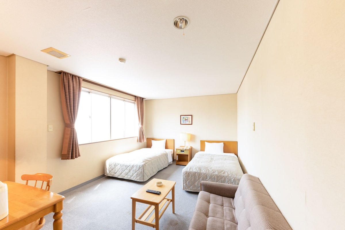 Una habitación de hotel con una cama, un sofá, una mesita y un escritorio.