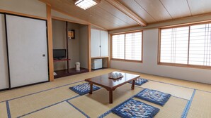 A traditional Japanese room with tatami flooring, a wooden table, and sliding doors. - Tabist Kanko Business Hotel Matsuyama Hida Takayama (Takayama)