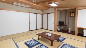A traditional Japanese room with tatami flooring, a wooden table with cups, and sliding doors. - Tabist Kanko Business Hotel Matsuyama Hida Takayama (Takayama)