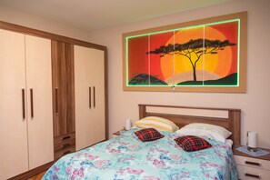 Une chambre à coucher comprenant un lit, des tables de chevet, une armoire et un tableau accroché au mur.