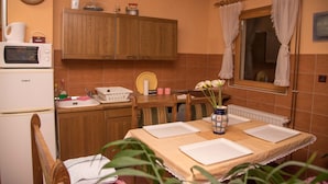A kitchen with wooden cabinets, a microwave, a sink, and a dining table set with white placemats. - Rooms Vlado (Daruvar)