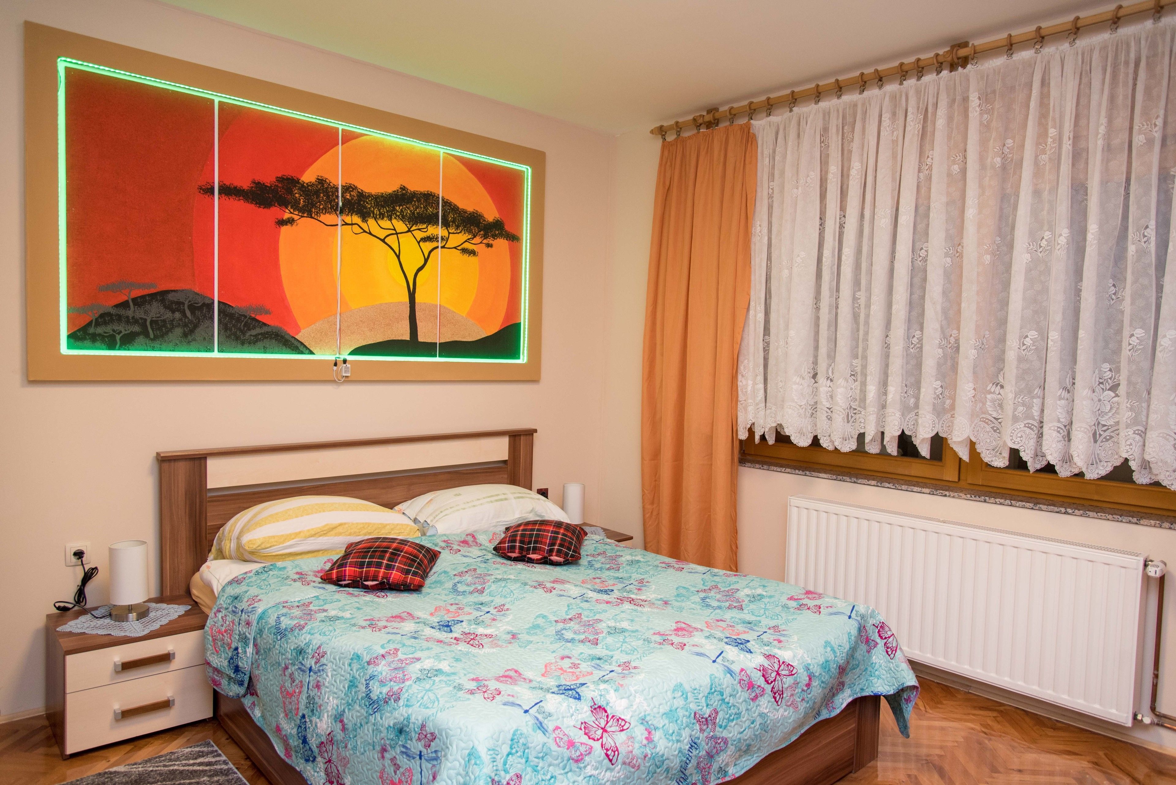 A bedroom with a bed, nightstand, and a wall-mounted painting.