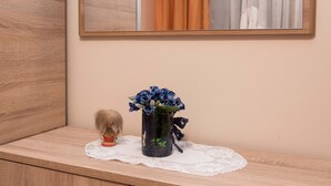 A wooden vanity with a mirror, a vase with flowers, and a small figurine. - Rooms Vlado (Daruvar)