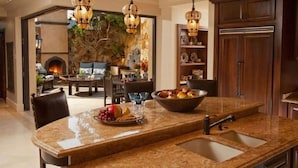 A kitchen with granite countertops, a double sink, and hanging pendant lights.
