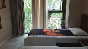 Un dormitorio con cama, una mesita de noche con lámpara y una ventana con cortinas.