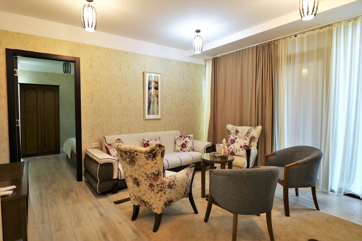 A living room with a sofa, two armchairs, a coffee table, and a painting on the wall.