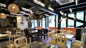 Un restaurante con mesas y sillas, adornos colgantes decorativos y un mural en la pared.