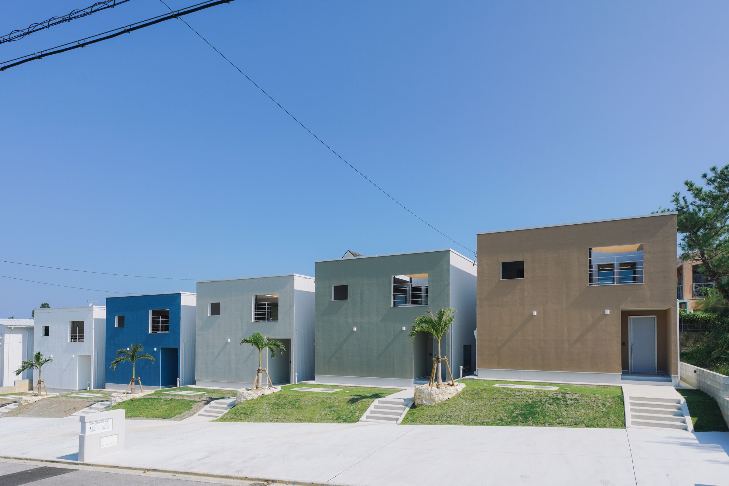 Une rangée d’immeubles modernes à plusieurs étages, dotés de toits plats et d’un design minimaliste.