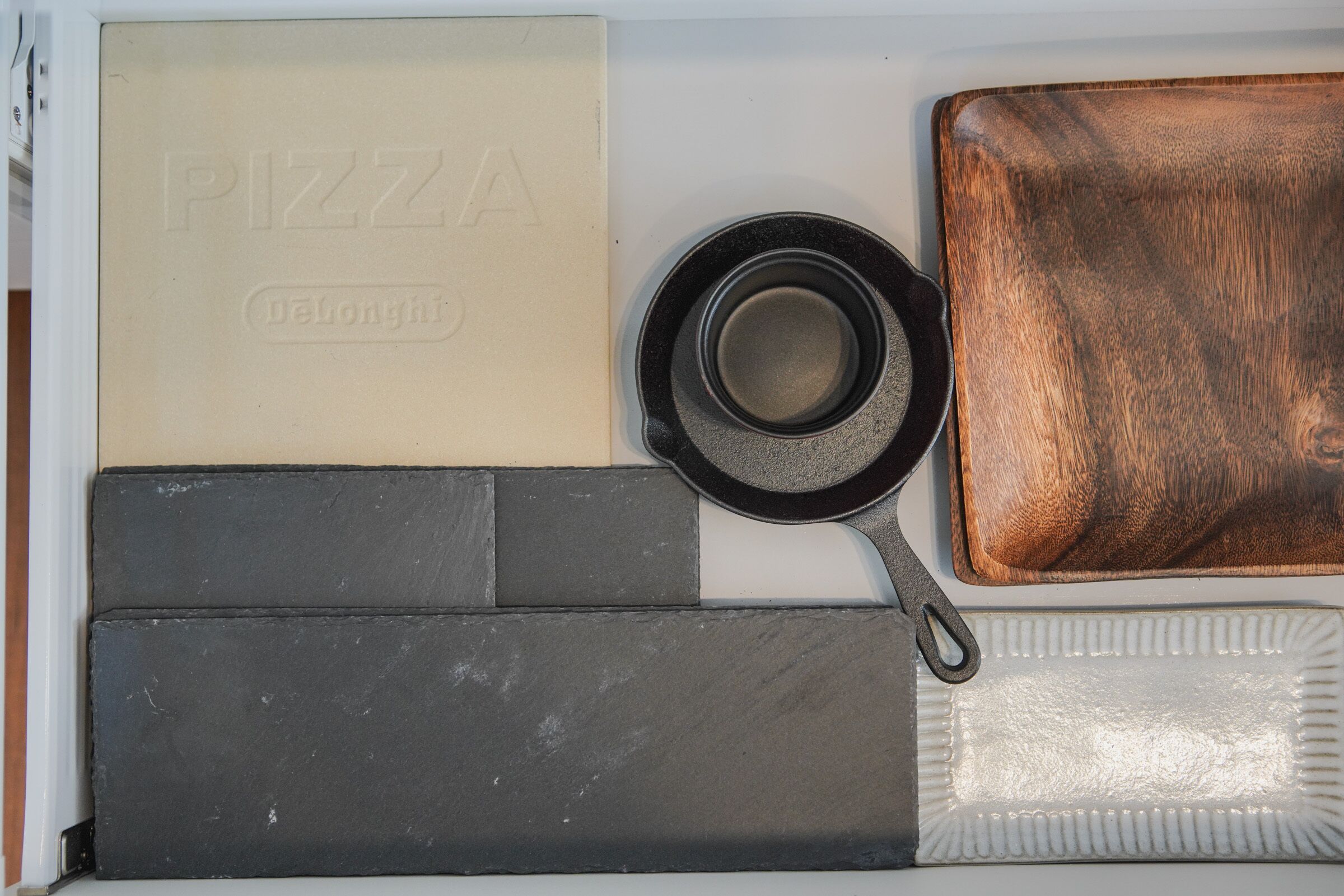 Una cocina con una caja de pizza, una sartén, una tabla de cortar y una bandeja para hornear.