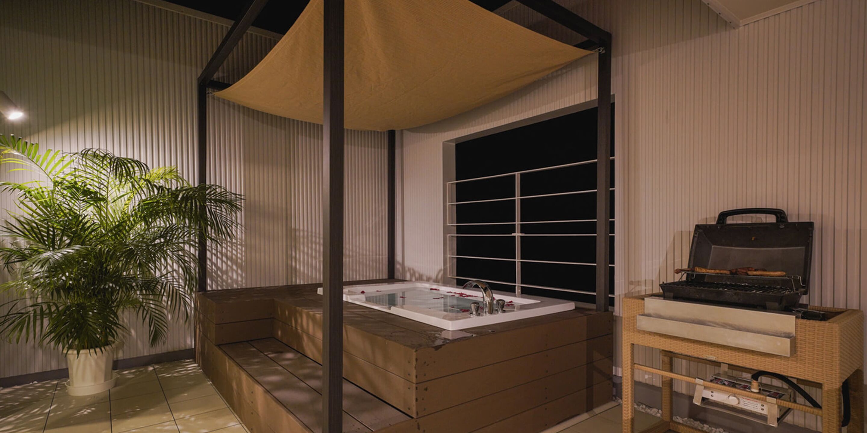 Un baño moderno con una bañera independiente, una planta grande en maceta y una parrilla.