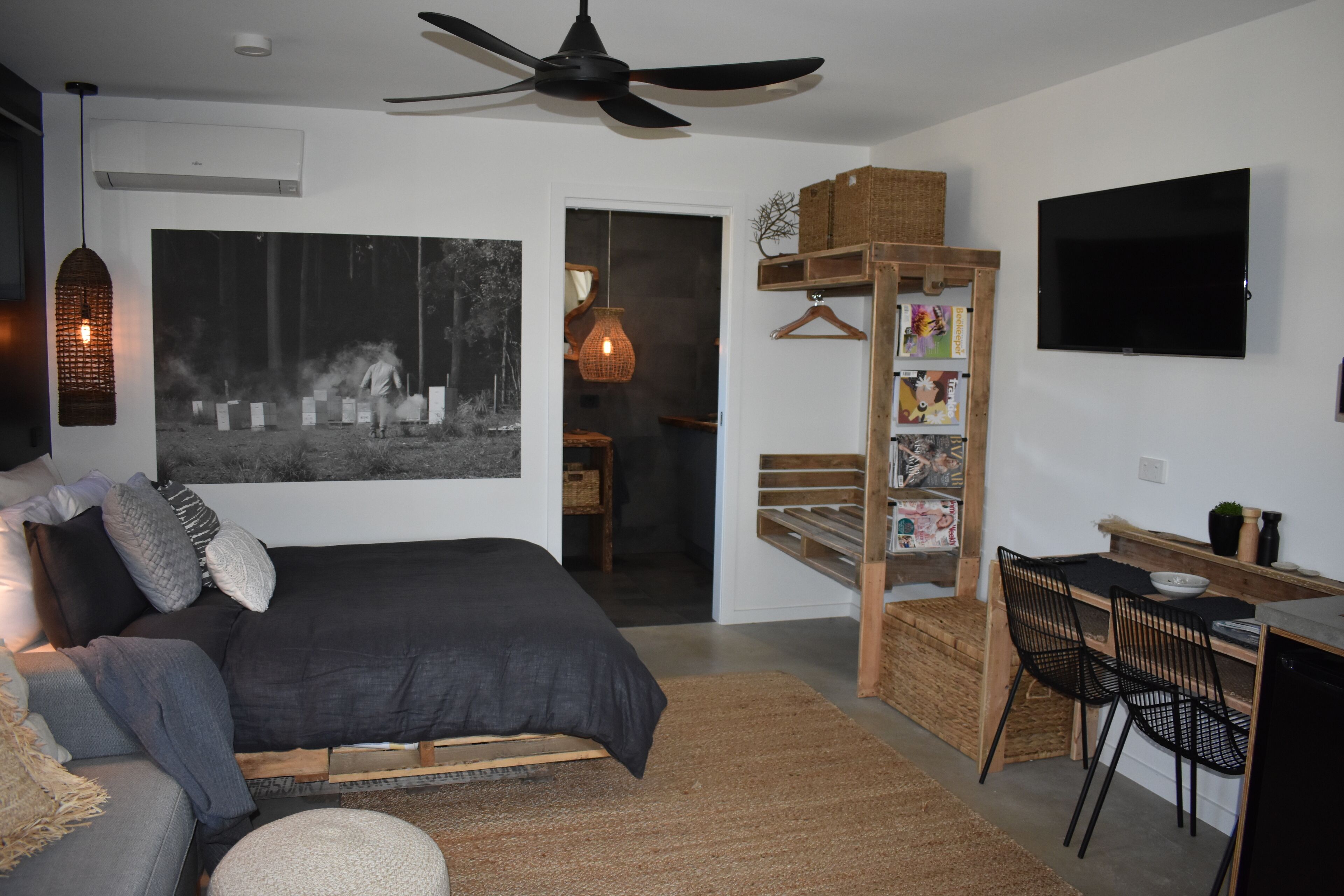 A modern bedroom with a bed, a desk, a chair, a TV, and a bookshelf.