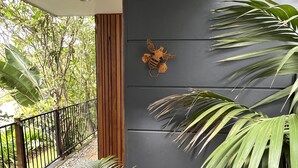 Un espacio exterior moderno con un muro negro, un banco de madera y plantas en macetas.