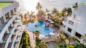 A resort with a central swimming pool surrounded by palm trees and lounge chairs. - Sunset Beach Resort & Spa- Beachfront Pirate Fire Show (Phu Quoc)