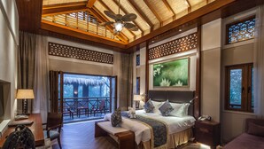 A spacious bedroom with a large bed, a desk, and a balcony with a view of the outdoors.