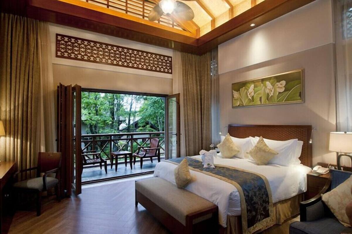 Un dormitorio amplio con una cama grande, vistas al exterior, un balcón y techo de madera.