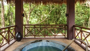 A hot tub with a wooden deck and a thatched roof structure.