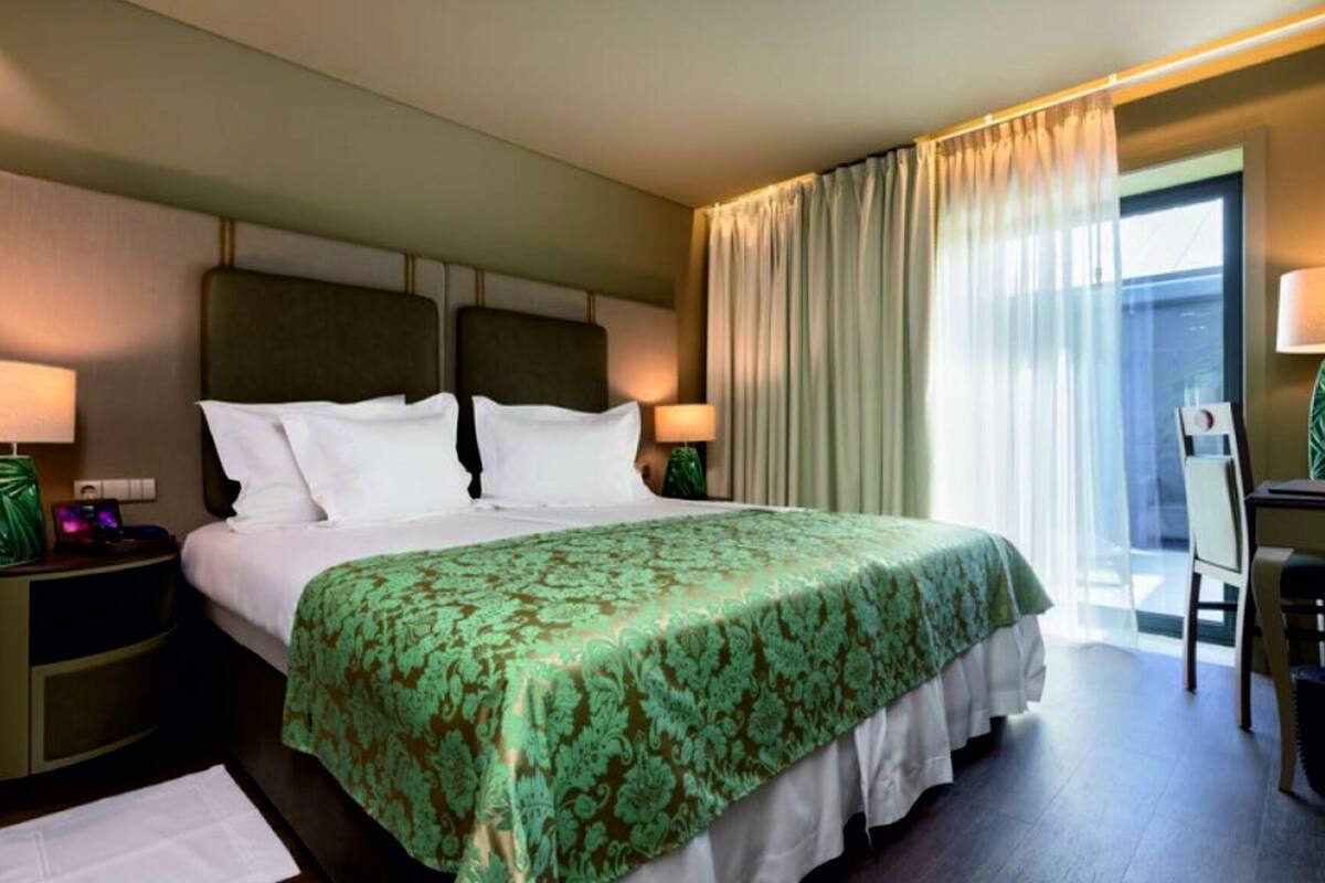 Ein Hotelzimmer mit einem großen Bett, zwei Nachttischen, einem Schreibtisch und einem Stuhl.