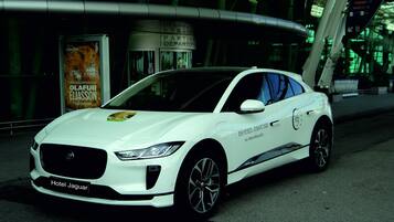 Un auto Jaguar blanco estacionado frente a un edificio con un letrero que dice "Hotel Jaguar".