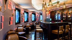 Zona de bar con asientos de cuero, barra y pared decorada con motivos.