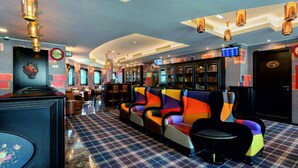 Un vestíbulo de hotel con mostrador de recepción, zona de estar colorida y un bar.