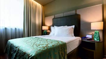 A hotel room with a large bed, two bedside tables, a desk, and a lamp.