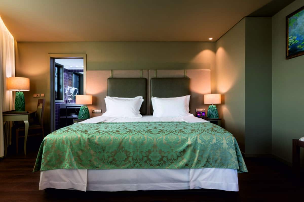 Ein Hotelzimmer mit einem großen Bett, zwei Nachttischen, einem Schreibtisch und einem Stuhl.