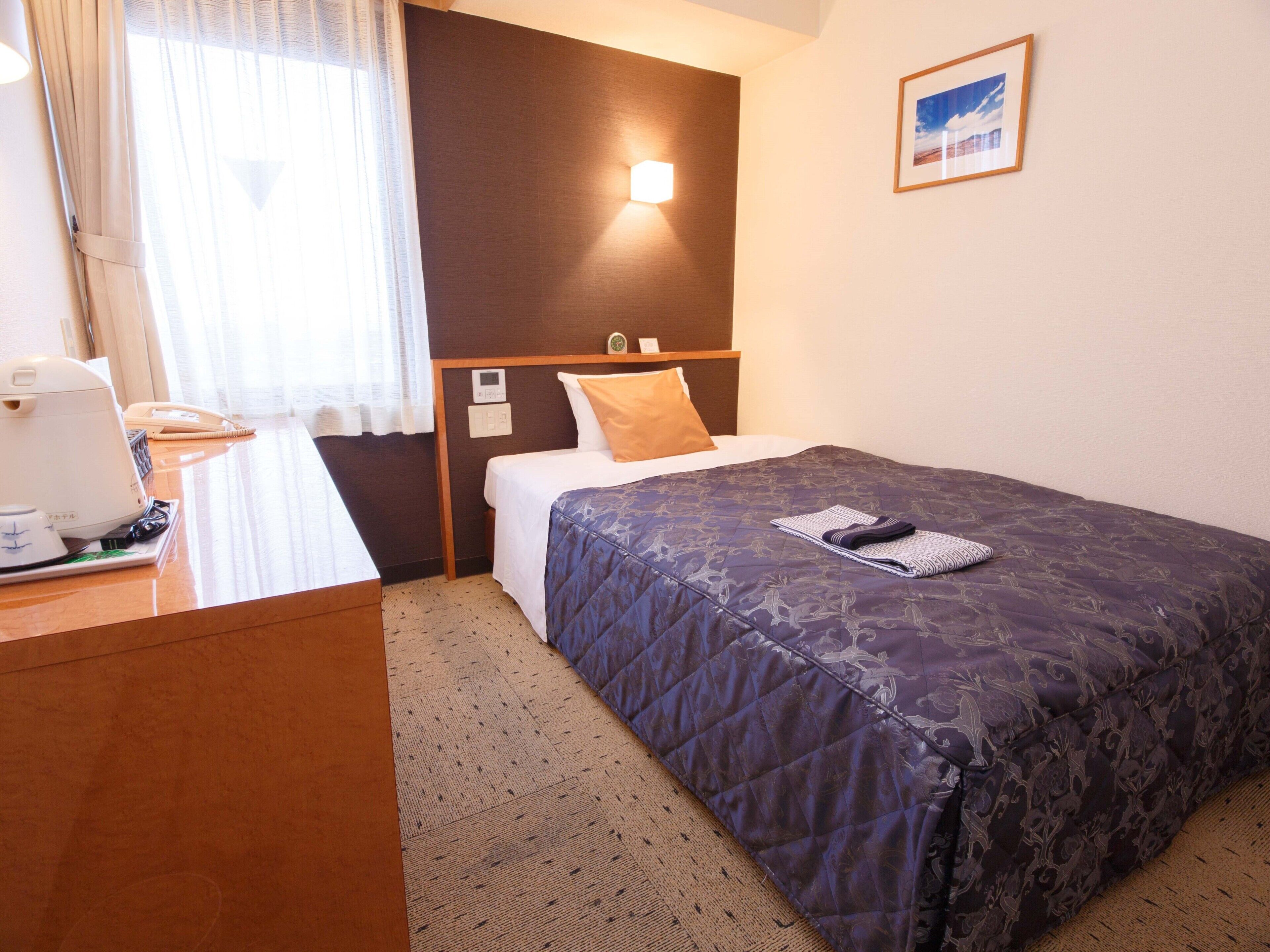 Une chambre d’hôtel avec un lit, une table de chevet, une lampe et un tableau encadré au mur.