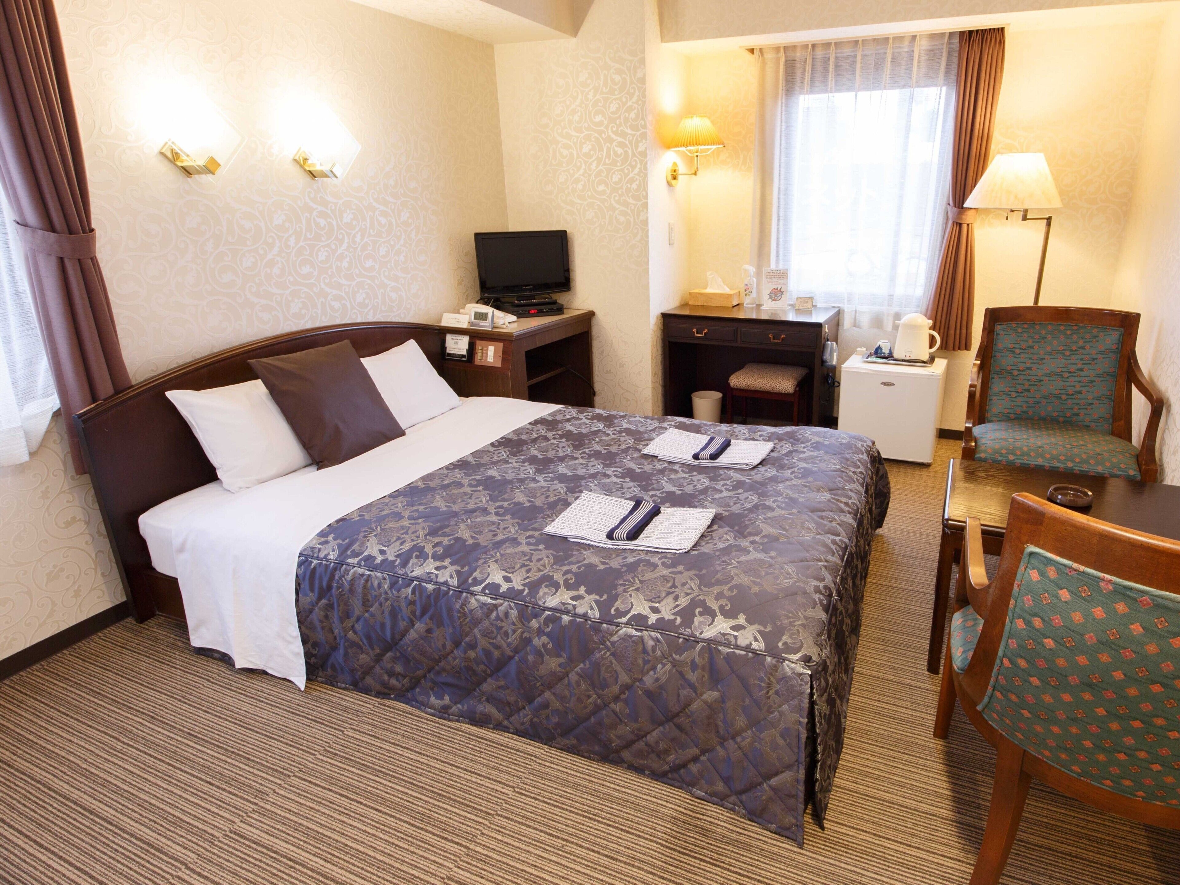 Une chambre d’hôtel équipée d’un lit, d’un bureau, d’une chaise, d’une télévision et d’une lampe.