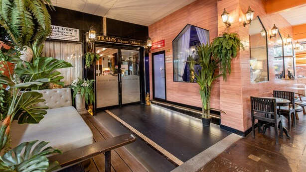 A hotel lobby with a reception desk, seating area, and a large window. - Sudyod House (Bangkok)