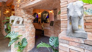 A lobby with brick walls, a reception desk, and a security guard statue. - Sudyod House (Bangkok)