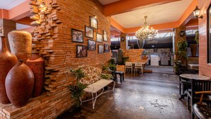 A restaurant with brick walls, framed pictures, and large vases. There are tables and chairs for dining. - Sudyod House (Bangkok)