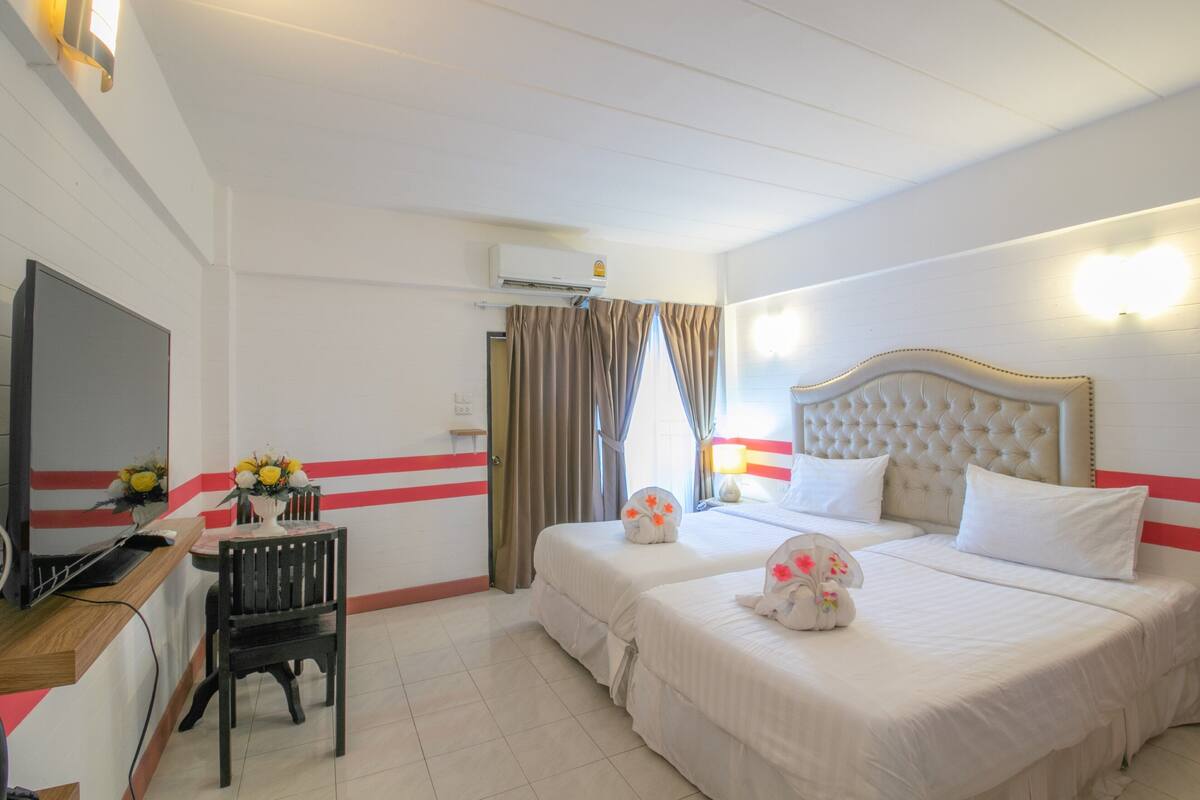 Une chambre d’hôtel avec deux lits, un bureau avec un ordinateur, une chaise et un téléviseur.