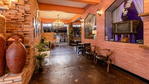 A spacious lobby with a brick wall, a chandelier, and a vintage microwave on display. - Sudyod House (Bangkok)