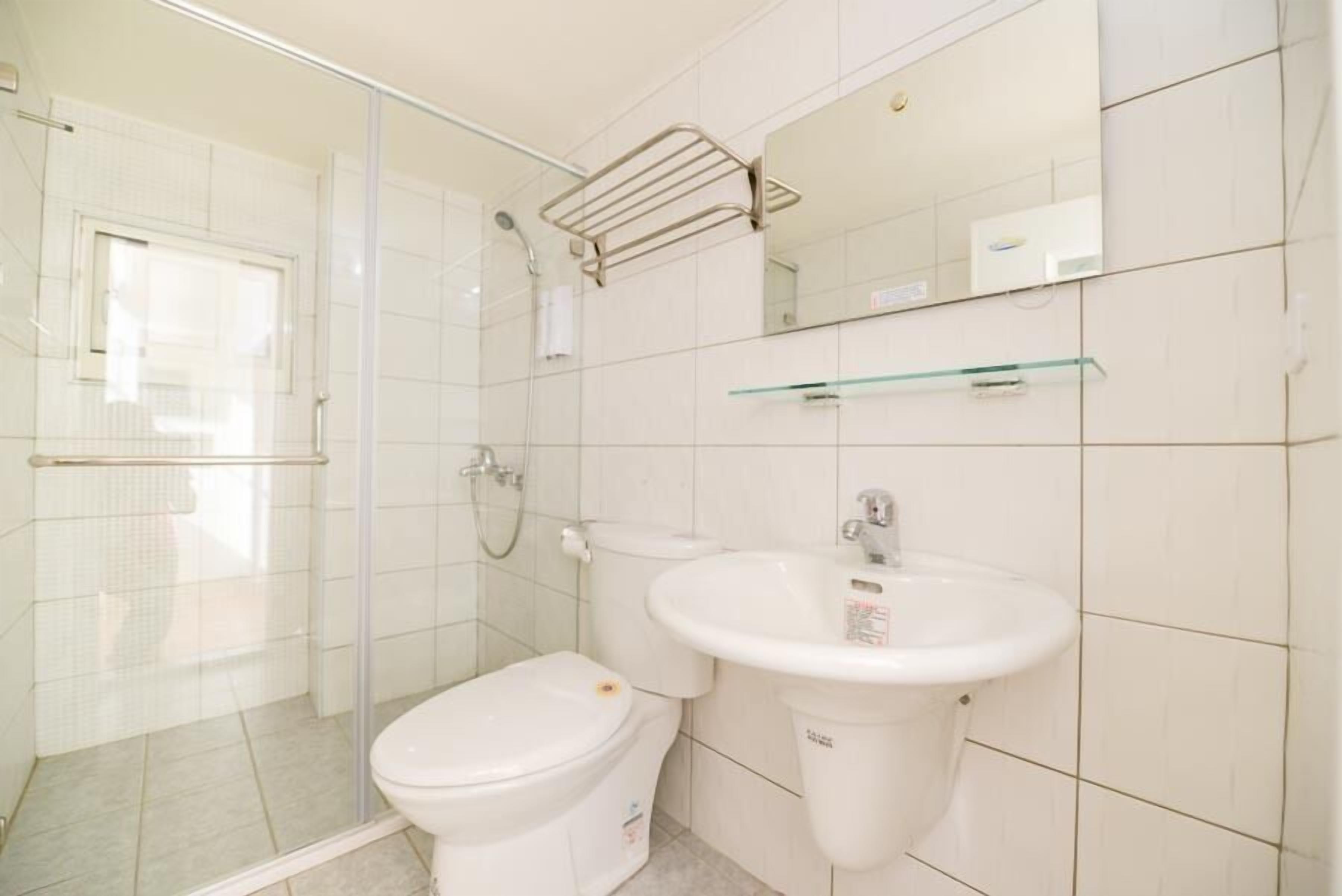 A bathroom with a toilet, sink, glass shower enclosure, and a towel rack.
