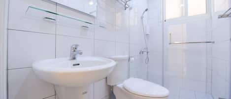 A modern bathroom with a white sink, toilet, and glass shower enclosure.