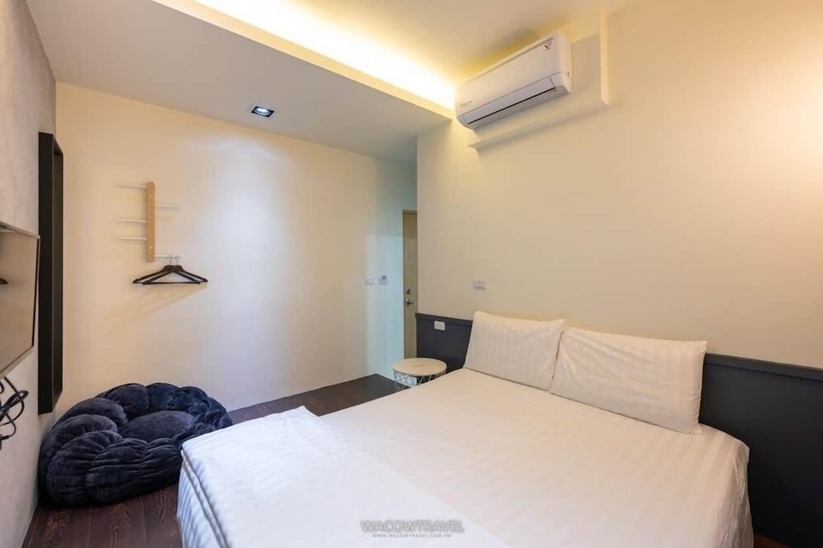 Habitación de hotel con cama, perchero, una mesita redonda y un equipo de aire acondicionado.
