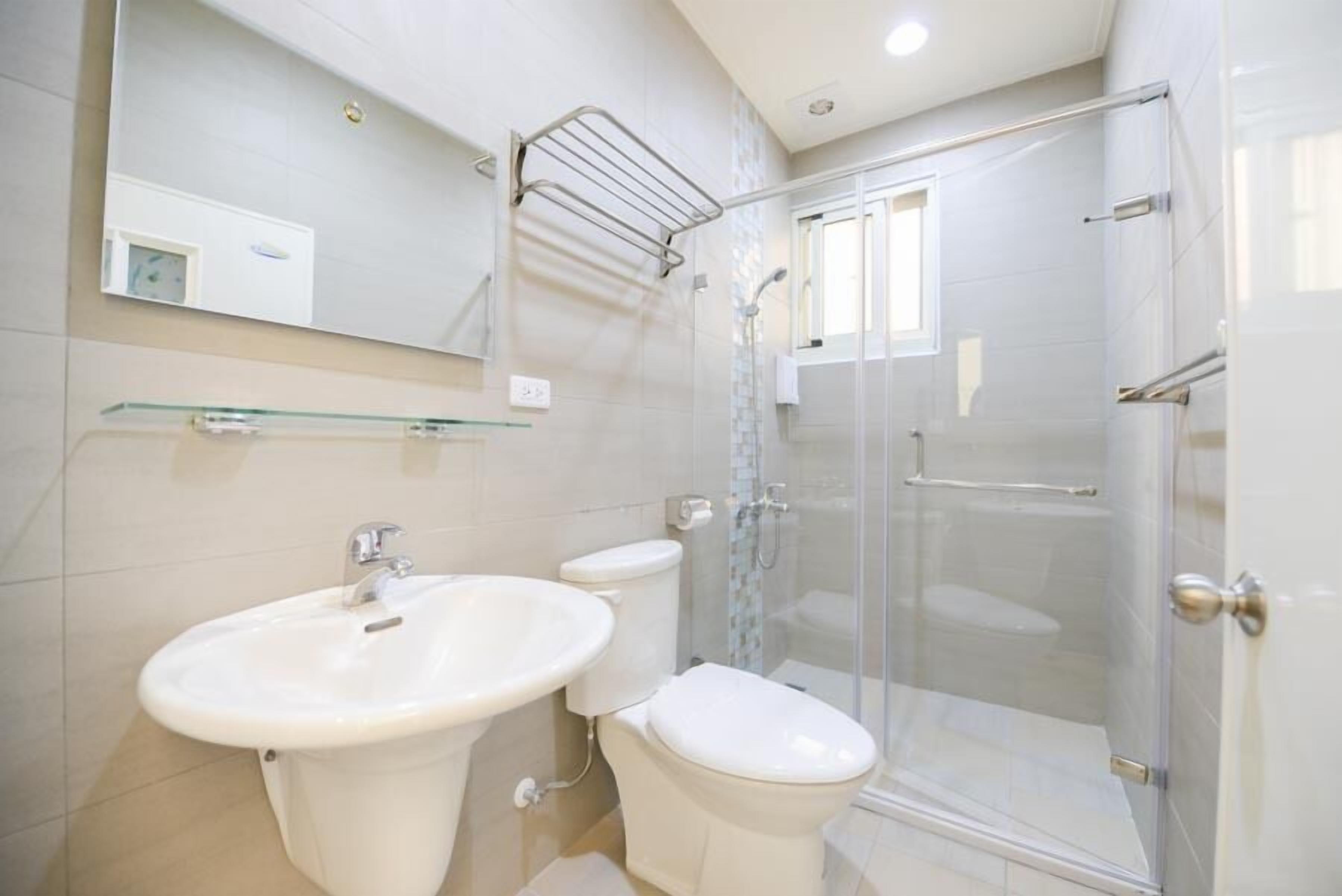 A modern bathroom with a glass shower enclosure, a sink, and a toilet.