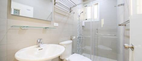 A modern bathroom with a glass shower enclosure, a sink, and a toilet.