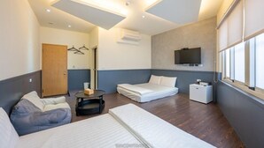 Una habitación de hotel moderna con una cama, un sofá, una mesita y un televisor montado en la pared.