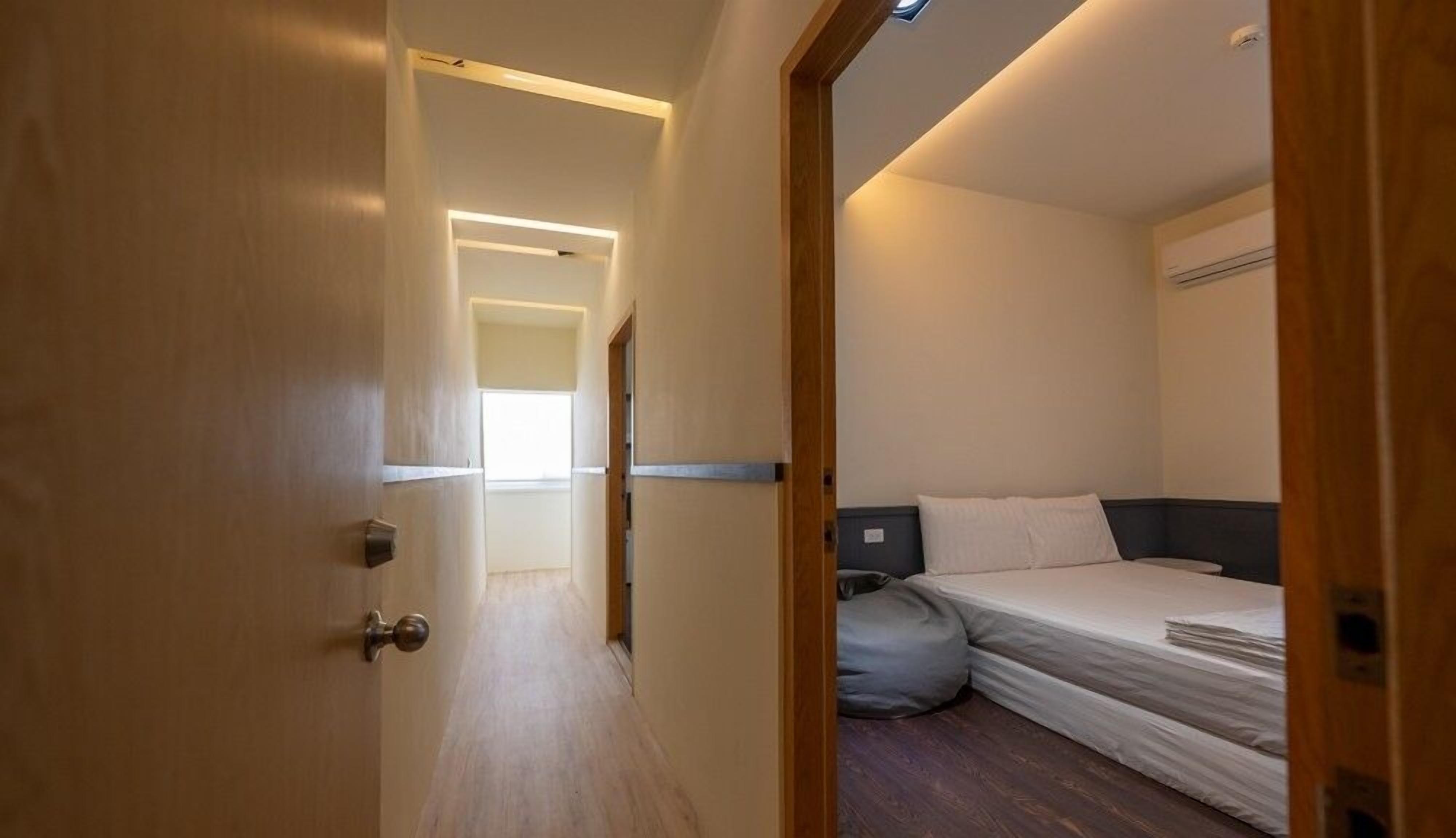 Una habitación de hotel con cama, mesita de noche y ventana.