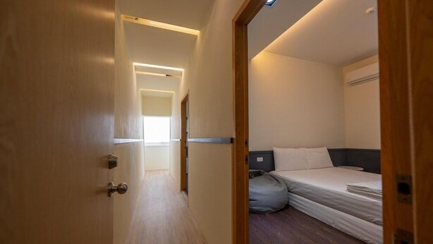 Una habitación de hotel con cama, mesita de noche y ventana.