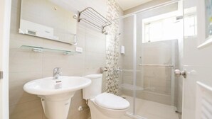Un baño con lavamanos, inodoro y cabina de ducha de vidrio.