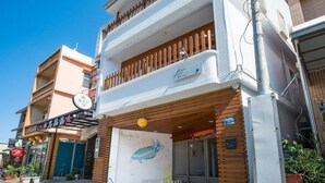 Un edificio de varios pisos con un balcón en el segundo piso, una tienda con un letrero y un cartel grande con una tortuga.