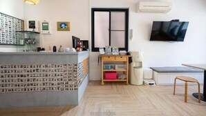 Un espacio moderno para vivir con área de cocina, una mesa de comedor, televisor montado en la pared y un gran ventanal con marco negro.
